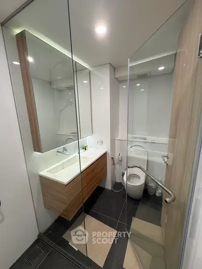 Modern bathroom with glass shower, sleek vanity, and contemporary fixtures.