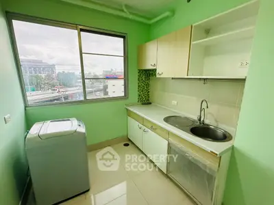 Bright kitchen with green walls, modern appliances, and city view from window.
