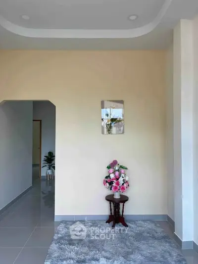 Elegant minimalist interior with floral decor and plush rug, showcasing modern design.