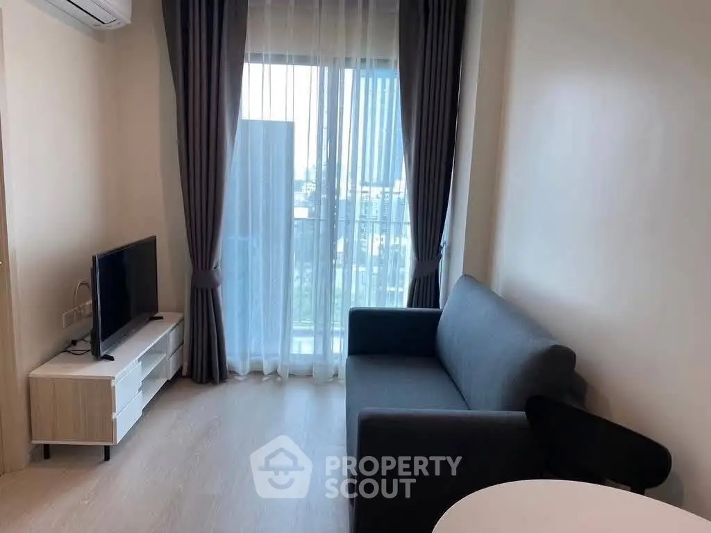 Modern living room with sleek furniture and city view through large window.
