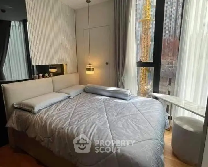 Modern bedroom with large windows and city view, featuring stylish decor and natural light.