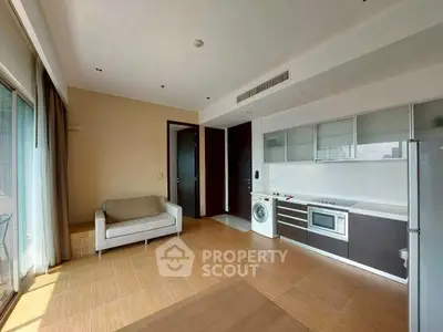 Modern open-plan living room with kitchen, featuring sleek appliances and cozy seating area.