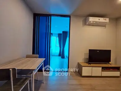 Modern living room with dining table, TV, and air conditioning in a stylish apartment.