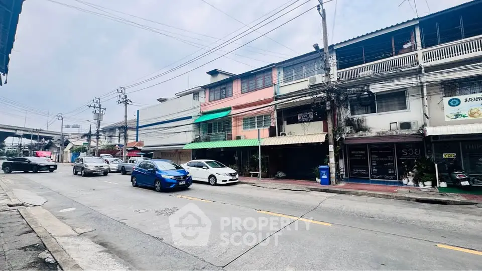 Street view of commercial buildings with parked cars, showcasing urban real estate potential.
