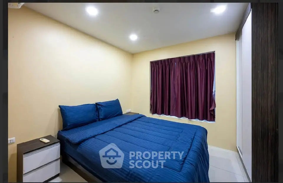 Cozy bedroom with blue bedding and maroon curtains, perfect for relaxation.