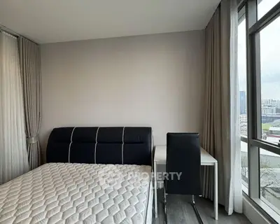 Modern bedroom with city view, featuring a sleek bed and study desk by the window.