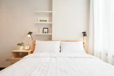 Modern bedroom with cozy white bedding and stylish decor, perfect for relaxation.