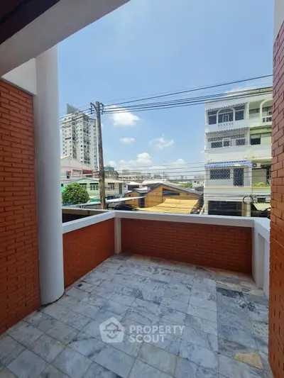 Spacious balcony with city view and brick accents, perfect for urban living.
