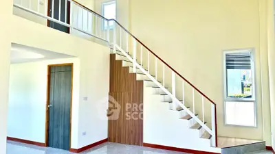 Modern interior with sleek staircase and high ceilings in a bright, open space.