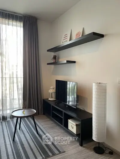 Modern living room with stylish decor, TV unit, and natural light from large window.
