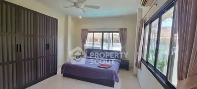 Spacious bedroom with large windows and modern furnishings in a serene setting.