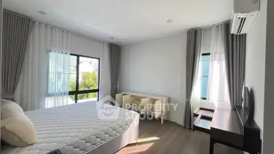 Spacious bedroom with large windows and modern furnishings in a bright, airy setting.