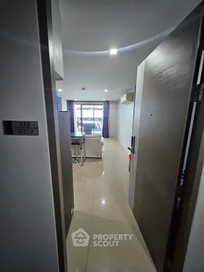 Spacious modern apartment entrance leading to a bright living area with large windows.
