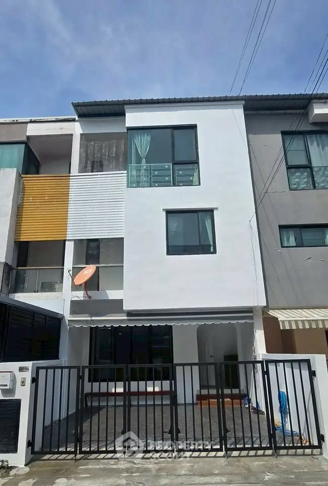 Modern three-story townhouse with gated entrance and large windows