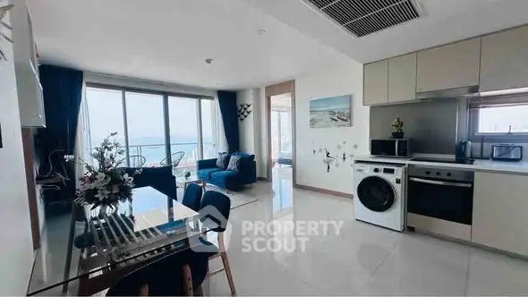 Modern open-plan living room with ocean view, featuring stylish kitchen and dining area.