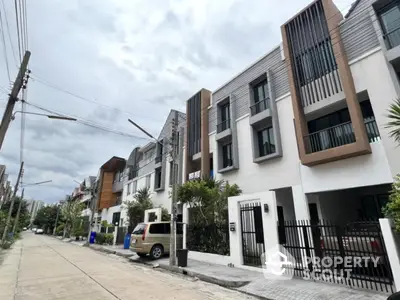 Modern townhouse exterior with sleek design and gated entrance on a quiet street.