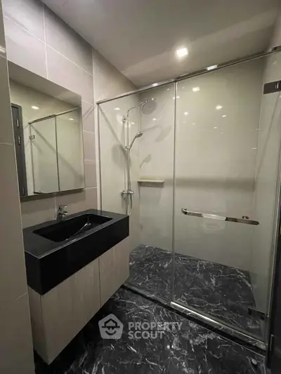 Modern bathroom with sleek black sink and glass shower enclosure