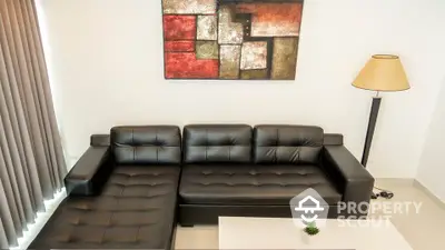 Modern living room with black leather sofa and abstract wall art