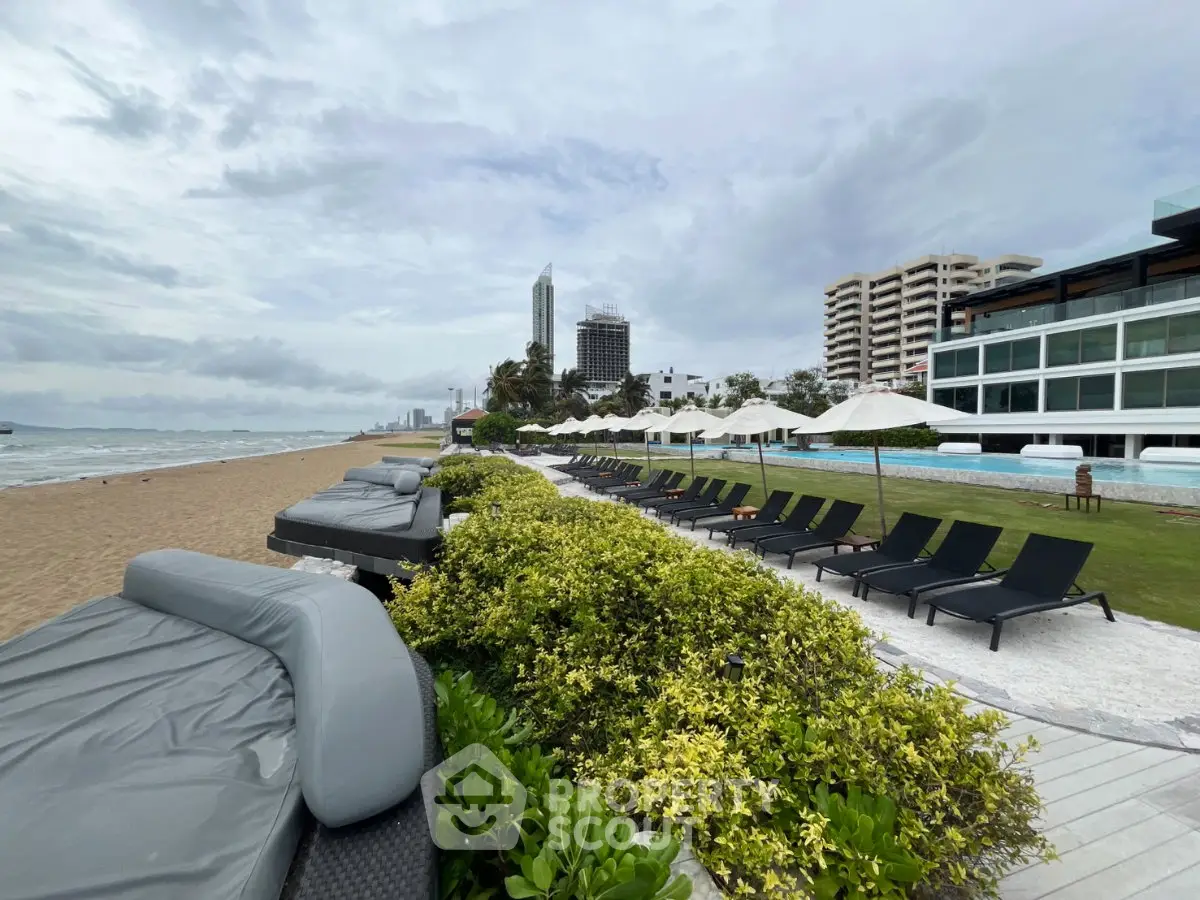 Luxurious beachfront property with poolside lounge chairs and stunning ocean views.