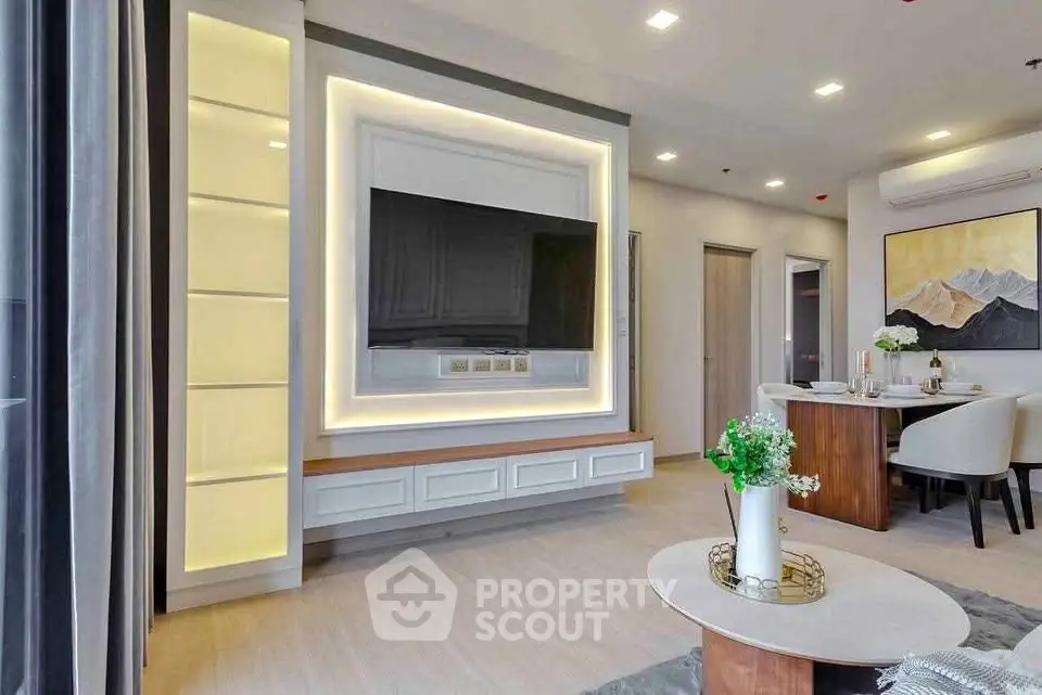 Modern living room with stylish decor and open layout, featuring a large TV and elegant dining area.