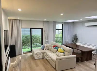 Spacious living room with modern decor, large windows, and garden view, perfect for family gatherings.