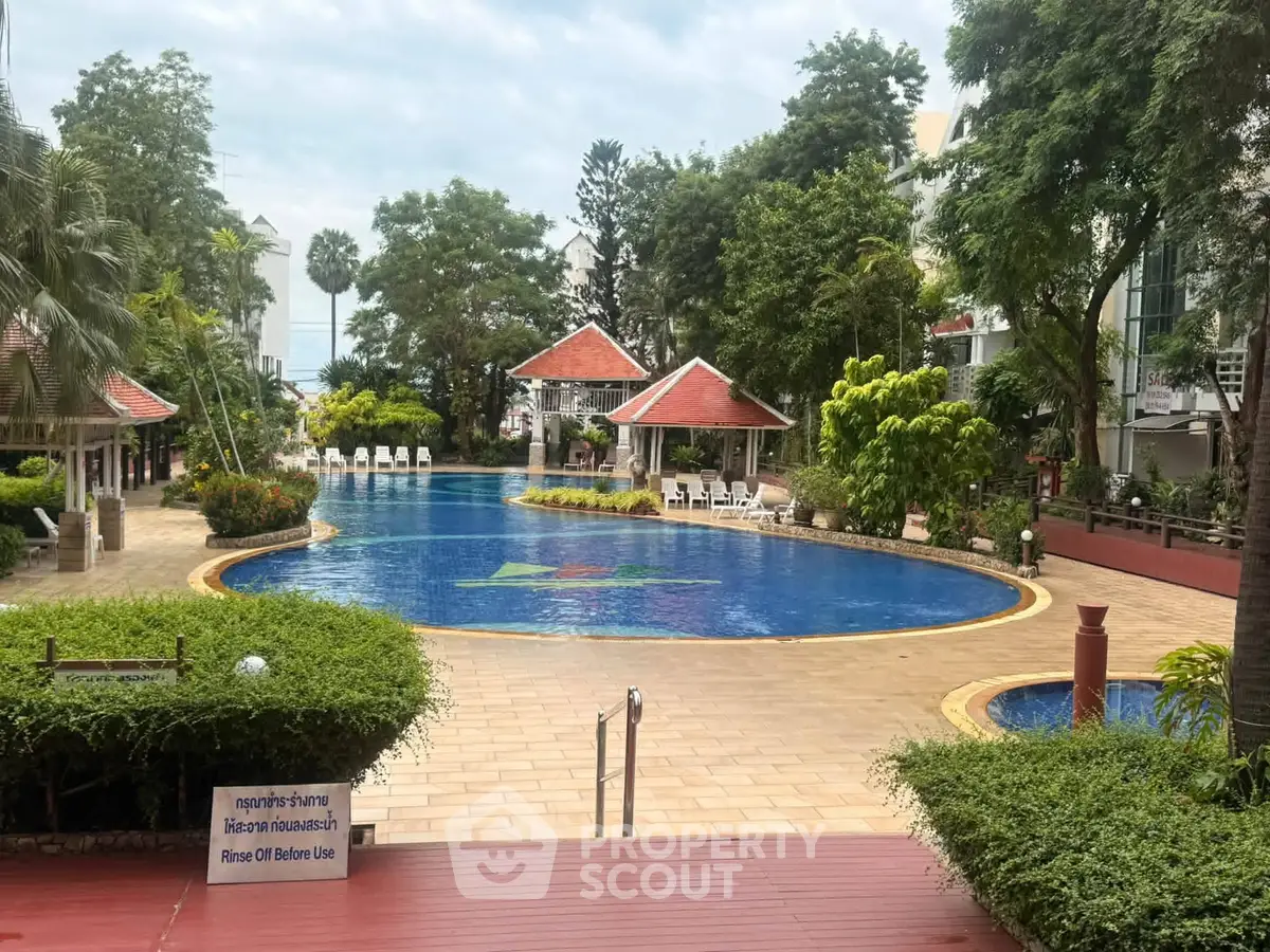 Luxurious residential pool area with lush greenery and sun loungers, perfect for relaxation and leisure.