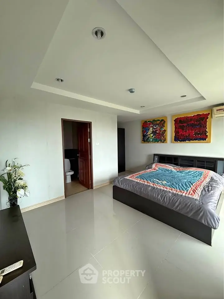 Spacious bedroom with modern decor and ensuite bathroom in a stylish apartment.