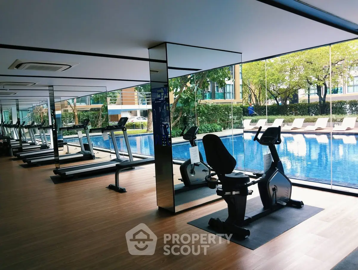 Luxurious gym with pool view in modern residential complex, featuring state-of-the-art fitness equipment.