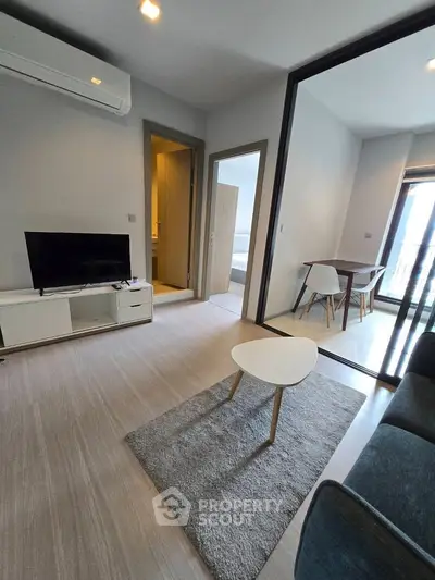 Modern living room with sleek furniture and open layout, featuring a cozy dining area.