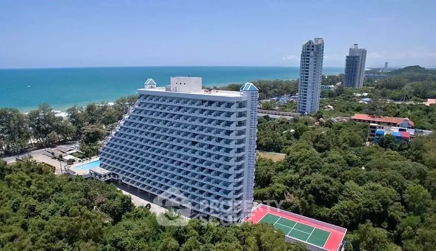 Stunning oceanfront high-rise with tennis court and lush greenery, offering breathtaking sea views.