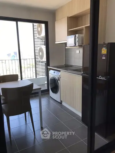 Modern kitchen with open layout, featuring a washing machine, microwave, and dining area with city view.