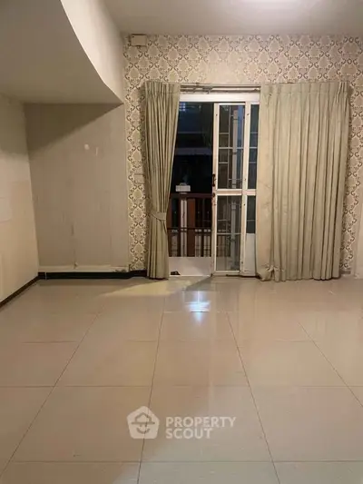 Spacious empty living room with tiled floor and large window with curtains.