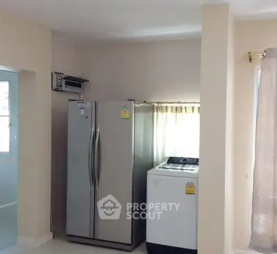Modern kitchen corner with fridge and washing machine in bright apartment