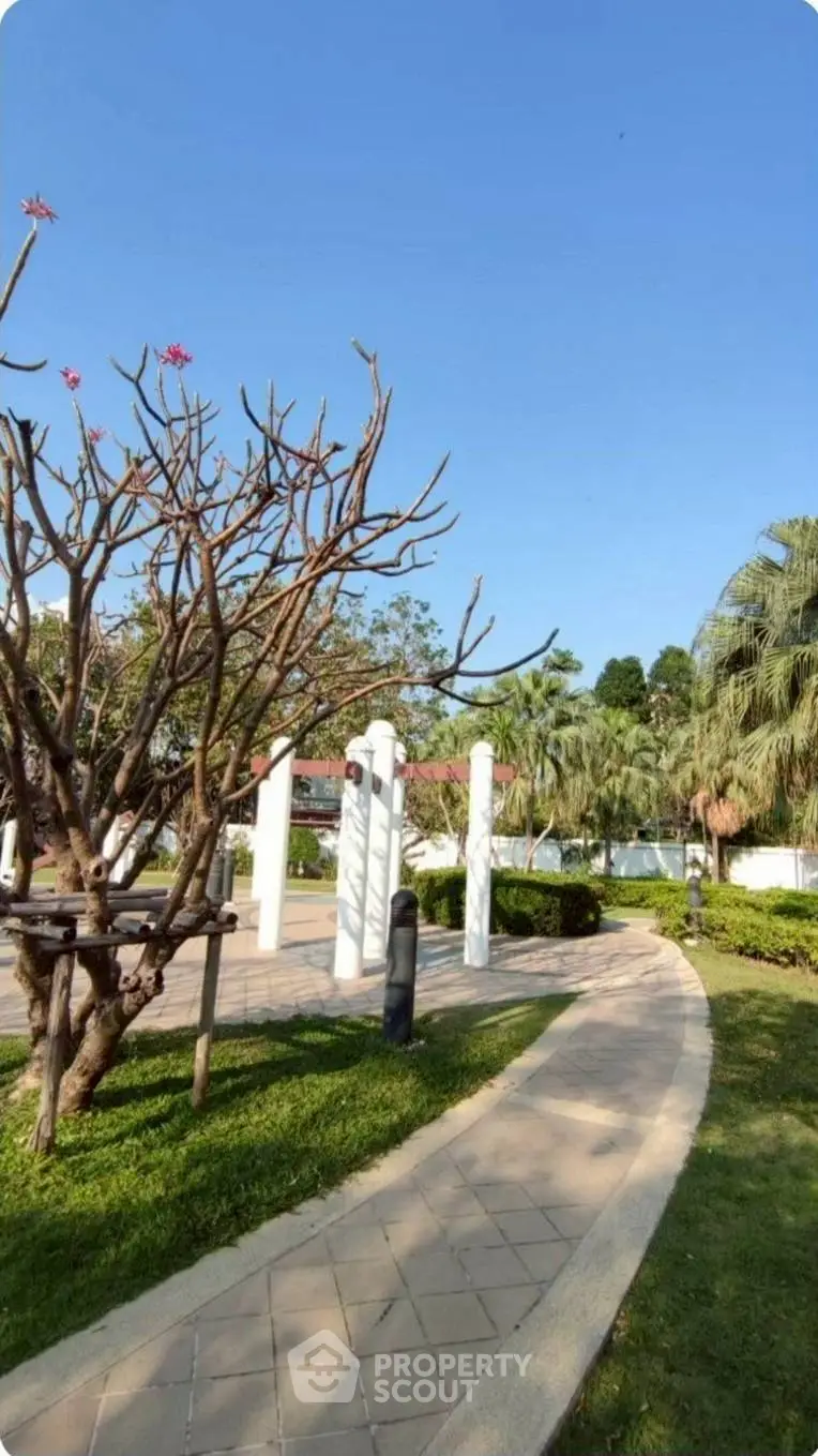 Serene garden pathway with lush greenery and clear blue sky
