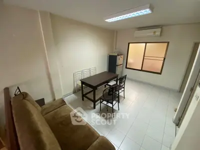 Cozy living room with dining table and sofa, featuring air conditioning and natural light.