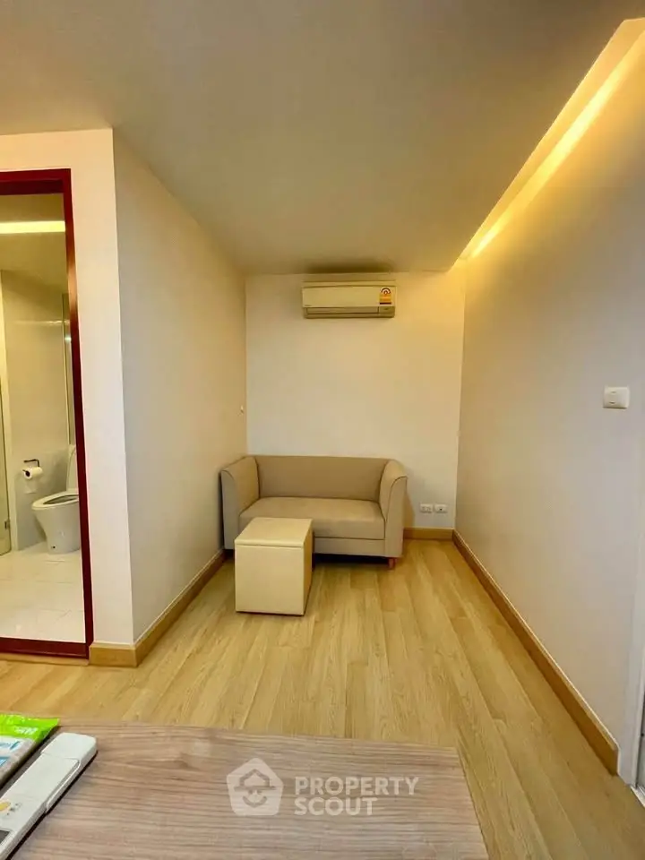 Cozy living room with modern sofa and air conditioning, featuring warm lighting and wooden flooring.