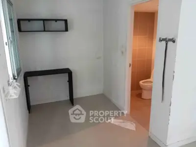 Compact room with minimal furniture and adjacent bathroom, ideal for efficient living space.