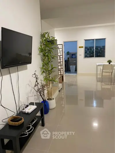 Modern living room with sleek TV setup and stylish decor in a spacious apartment.