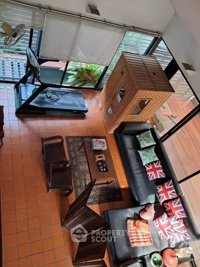 Spacious living room with treadmill, cozy seating, and large windows for natural light.