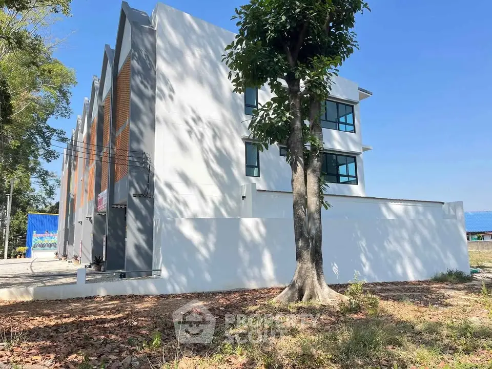 Modern multi-story building with sleek design and large windows, surrounded by trees and open space.