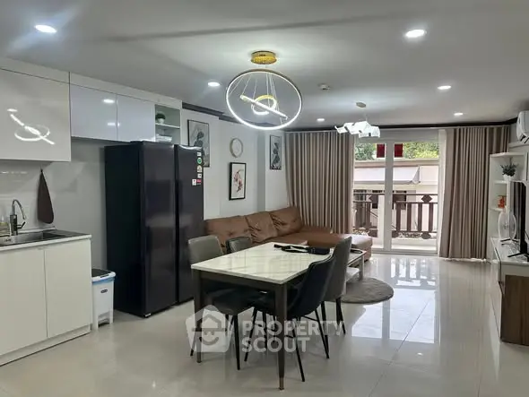 Modern open-plan living room with kitchen, featuring sleek furniture and stylish lighting.