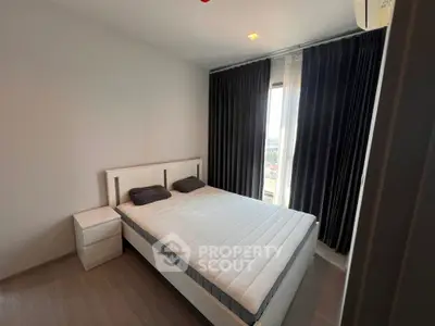 Modern bedroom with minimalist design and large window offering natural light.