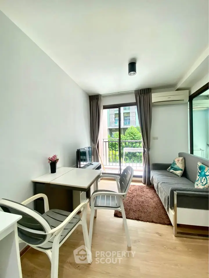 Modern living room with balcony view, stylish furniture, and natural light in urban apartment.