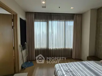 Spacious bedroom with large window and elegant curtains, offering ample natural light and a cozy atmosphere.