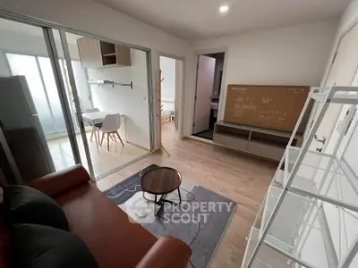Modern living room with sleek furniture and a 50-inch TV, adjacent to a dining area and balcony.