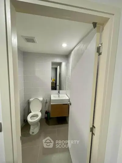 Modern bathroom with sleek design and compact layout, featuring a toilet and sink.