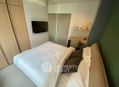 Cozy modern bedroom with built-in wardrobe and wall-mounted TV, featuring a comfortable bed and a compact study area with ample lighting.