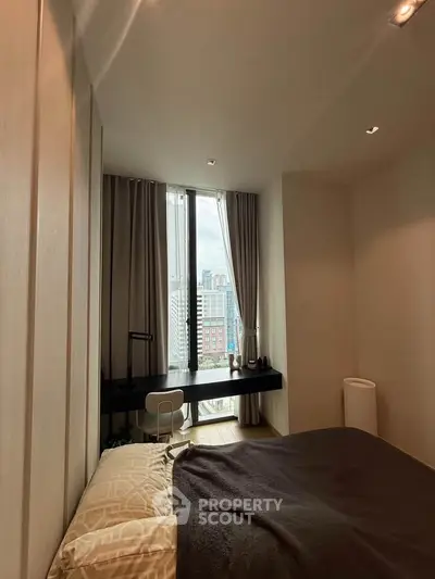 Cozy bedroom with city view, featuring a modern desk and large window for natural light.