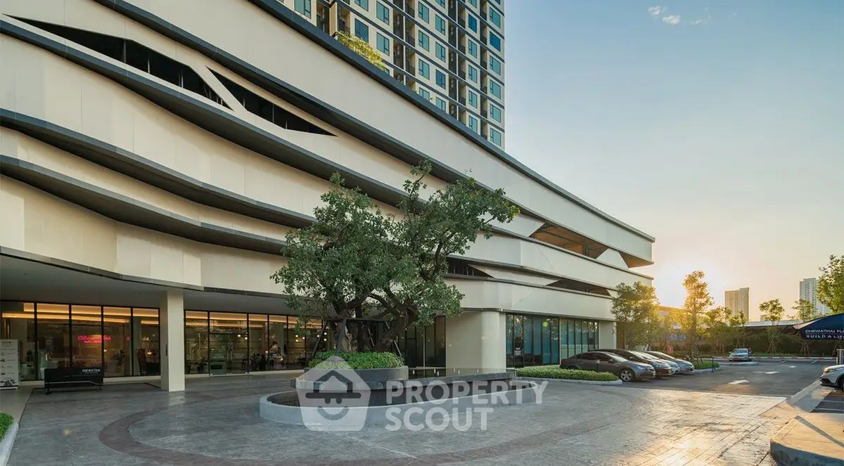 Modern building entrance with sleek design and landscaped driveway, perfect for urban living.