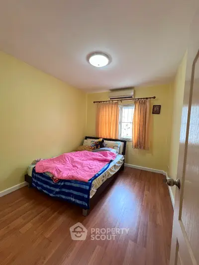 Cozy bedroom with wooden flooring and natural light